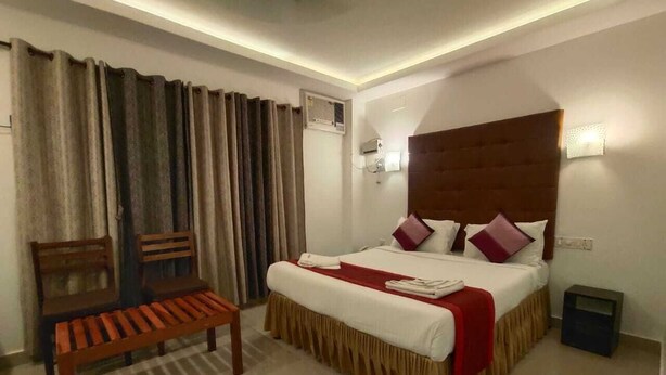 Habitación de hotel con cama, un banco, una mesita de noche y un aire acondicionado de pared.
