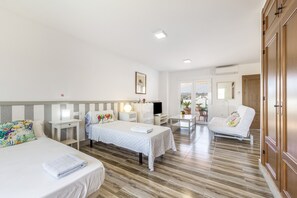 Ein Hotelzimmer mit zwei Betten, einem Schreibtisch, einem Stuhl, einem Fernseher und einem Kleiderschrank.