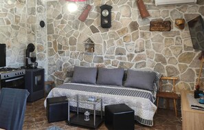 A stone-walled room with a bed, a coffee machine, a stove, and a wooden sign. - Lovely home in Gradac (Gradac)