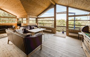 Ein Holzblockhaus-Interieur mit einer Couch, einem Tisch und großen Fenstern mit Blick ins Freie.