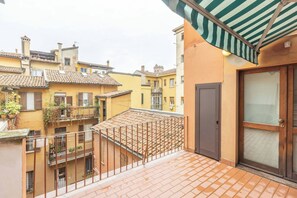 A balcony with a metal railing, a door with a glass panel, and a tiled roof. - Unione (Bologna)
