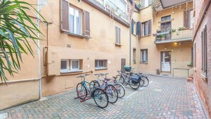 Un patio con bicicletas aparcadas, suelo de ladrillo y edificios con balcones.