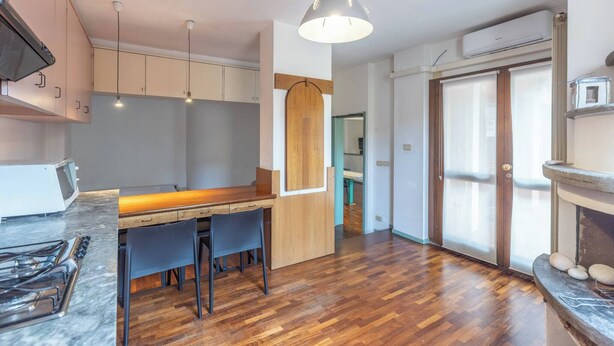 Una cocina moderna con una mesa de comedor de madera, sillas y una lámpara colgante.