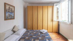 Un dormitorio con una cama, un armario de madera, una ventana y un cuadro enmarcado en la pared.