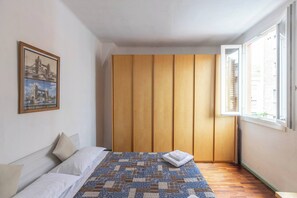 A bedroom with a bed, a wooden wardrobe, a window, and a framed picture on the wall. - Unione (Bologna)