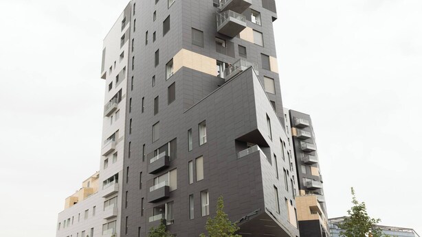Een meerlaags gebouw met balkons, grote ramen en een modern architectonisch ontwerp.