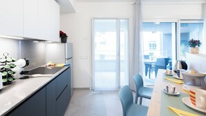 Een moderne keuken met een eethoek, een schuifdeur naar buiten en uitzicht op de stad.
