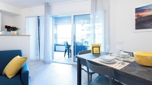 Een moderne woonkamer met een blauwe bank, een eettafel gedekt met borden en glazen, en een gele mand.