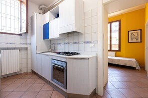 Eine kleine Küche mit Herd, Backofen und weißen Schränken.