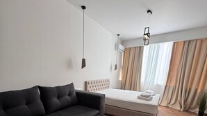 A modern hotel room with a sofa, a round wooden coffee table, a bed, and a large window with curtains. - Athenian Stay 305 Apartment Monastiraki (Athens)