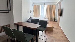 A modern living space with a dining area, a sofa, a TV mounted on the wall, and a window with curtains. - Athenian Stay 305 Apartment Monastiraki (Athens)