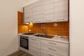 Eine kleine Küche mit Gaskochfeld, Backofen und Spüle.