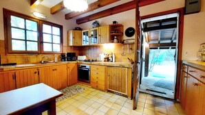 A kitchen with wooden cabinets, a sink, a stove, and a clock on the wall. - Charming country house between the forest and the ocean - Contis (Lit-et-Mixe)