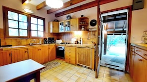 A kitchen with wooden cabinets, a sink, a stove, and a clock on the wall. - Charming country house between the forest and the ocean - Contis (Lit-et-Mixe)