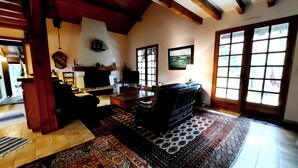 A living room with a fireplace, a sofa, a television, and a large window. - Charming country house between the forest and the ocean - Contis (Lit-et-Mixe)