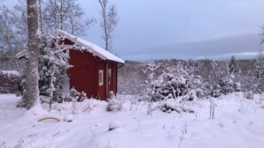 A red building surrounded by snow-covered trees and shrubs. - Log cabin with hot tub and views (Bondemölla)