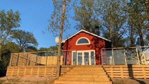 A red building with a wooden staircase leading to a glass door, surrounded by trees. - Log cabin with hot tub and views (Bondemölla)