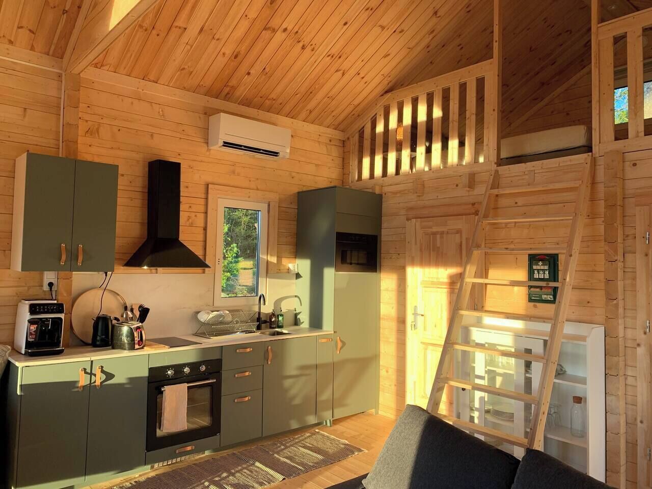A compact kitchen with a stove, oven, sink, and a window.
