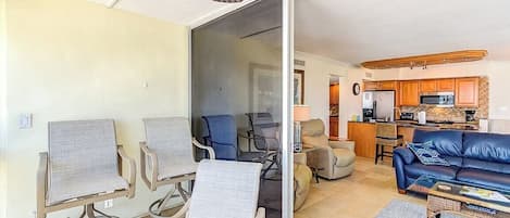 A living room with a sofa, chairs, a coffee table, and a sliding glass door leading to a kitchen.