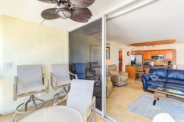 A living room with a sofa, chairs, a coffee table, and a sliding glass door leading to a kitchen. - Unit 97- 2 Bedroom and 2 Bathroom Condominium with Partial South Views. (Sarasota)