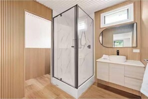 A modern bathroom with a glass shower enclosure, a wooden vanity, and a large mirror. - Arielle’s haven (Cedar Creek)