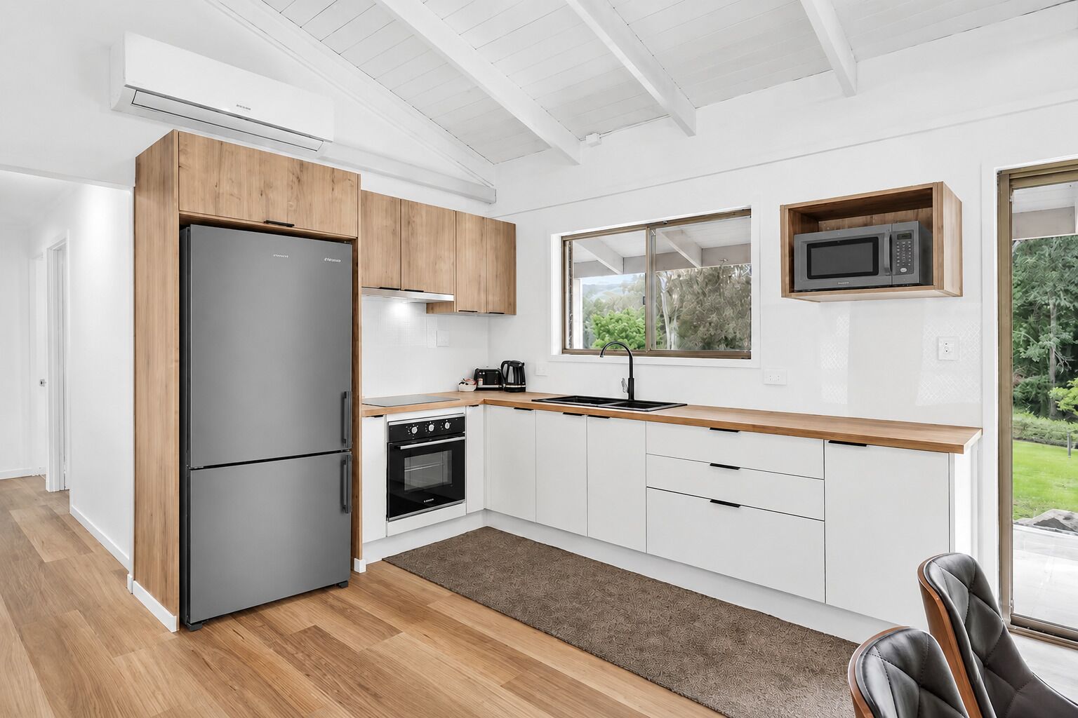 A modern kitchen with a refrigerator, oven, microwave, and wooden cabinets.