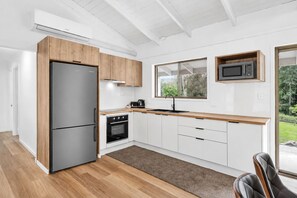 A modern kitchen with a refrigerator, oven, microwave, and wooden cabinets. - Arielle’s haven (Cedar Creek)
