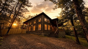 A rustic cabin with a stone foundation, large windows, and a porch. - Romantic Retreat with Hot Tub & Fire Pit in Broken Bow, Oklahoma (Broken Bow)