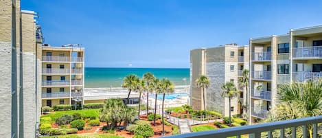 Un hotel frente a la playa con varios balcones, una piscina y un jardín bien cuidado.