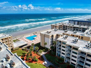 A high-rise hotel with a rooftop pool, ocean view, and multiple balconies. - Wake Up to Ocean Views | Castle Reef 411 (New Smyrna Beach)