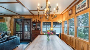 Un interno in legno con un tavolo da pranzo, un lampadario e ampie finestre.