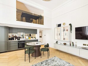 A modern kitchen with a dining area, a TV mounted on the wall, and a large window. - Decadent and Exquisite Holland Park Duplex (Greater London)