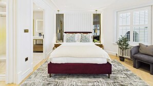 A spacious bedroom with a large bed, bedside tables, a dresser, a mirror, and a window with blinds. - Decadent and Exquisite Holland Park Duplex (Greater London)