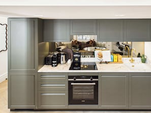 A modern kitchen with grey cabinetry, a built-in oven, and a coffee machine. - Decadent and Exquisite Holland Park Duplex (Greater London)