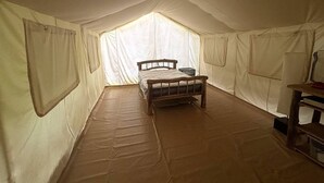 Una tienda de campaña con cama, una mesita y una ventana.