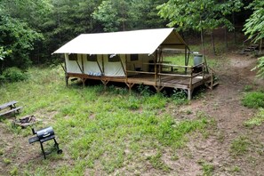 Una carpa con una terraza de madera y una mesa de picnic cerca.
