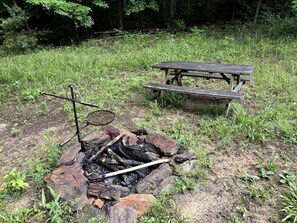 Una mesa de picnic y una fogata en un área boscosa.