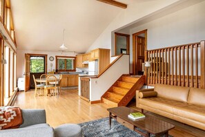 Amplia sala de estar con un sofá, una mesa de centro y una zona de comedor con muebles de madera.