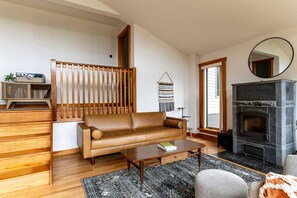 Una sala de estar con sofá, mesa de centro, chimenea y escalera de madera.