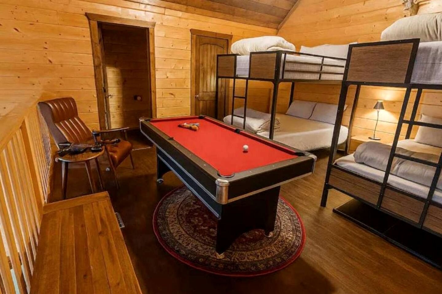 Una habitación acogedora con mesa de billar, literas y detalles de madera.