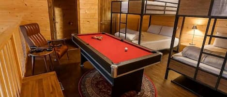 Una habitación acogedora con mesa de billar, literas y detalles de madera.