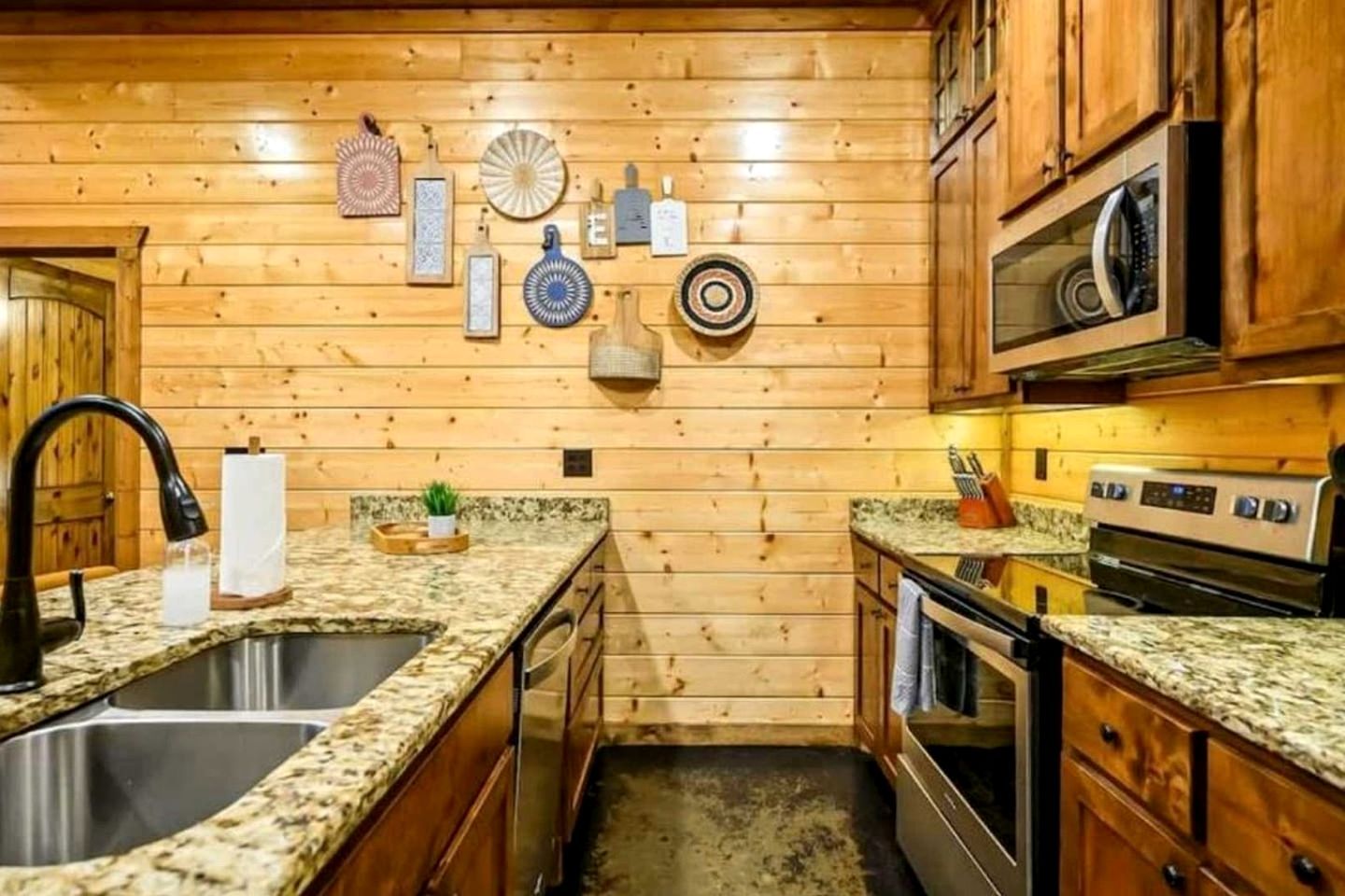A wooden-paneled kitchen with granite countertops, stainless steel sink, and a built-in oven.