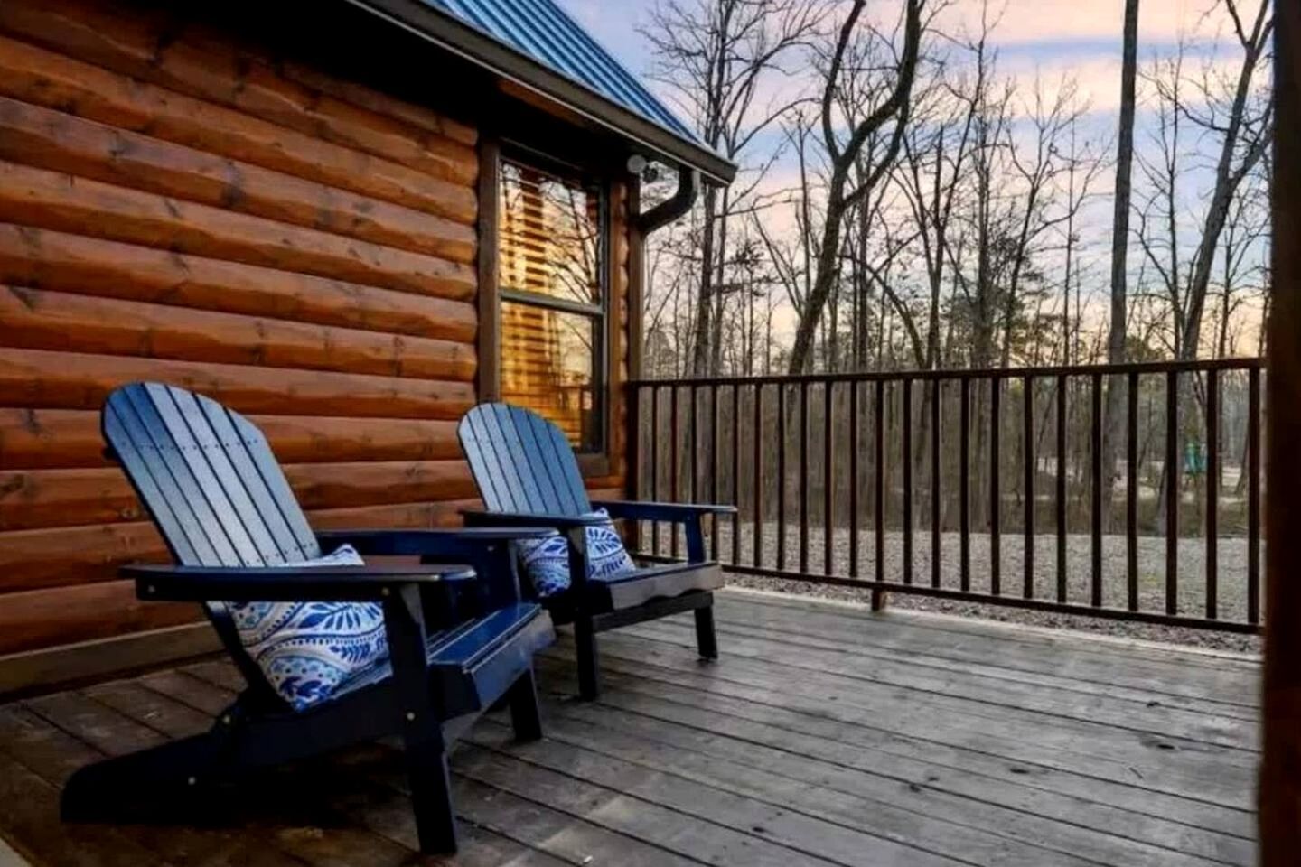 Eine Blockhütte mit zwei Adirondack-Stühlen auf einer Holzterrasse.