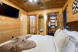 A wooden cabin room with a bed, a television, and a mirror. - Luxury Pine Ridge Lodge with Hot Tub, Sauna & Game Room in Broken Bow, OK (Broken Bow)
