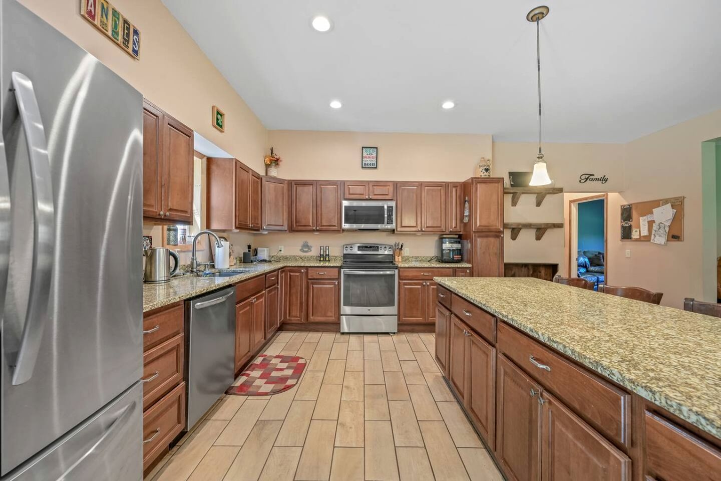 Una cocina con armarios de madera, electrodomésticos de acero inoxidable y encimera de granito.