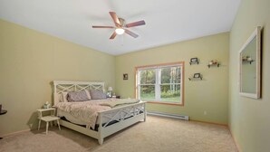 A bedroom with a bed, a nightstand, a ceiling fan, a window, and a mirror. - Peaceful Estate Designed for Connection & Relaxation in Andes, New York (Andes)