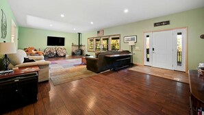 A living room with a fireplace, a television, a sofa, and a dining area. - Peaceful Estate Designed for Connection & Relaxation in Andes, New York (Andes)