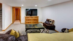Ein Wohnzimmer mit Fernseher, Holzschrank, Sofa und Couchtisch.