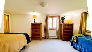 Ein Schlafzimmer mit zwei Betten, einem Fenster mit Vorhängen, einem Schminktisch und einer Lampe.