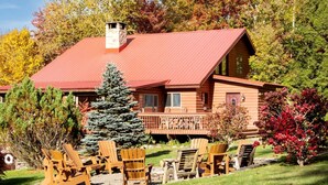 Eine Blockhütte mit rotem Dach, einer Terrasse und Sitzgelegenheiten im Freien.